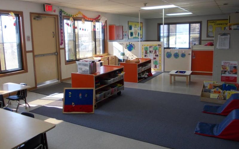 Empty classroom with orange storage shelves, tables, and decorations