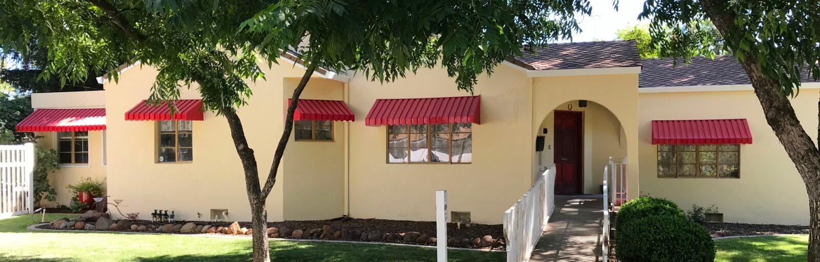 Cream-colored building with red awnings over windows and an arched entryway
