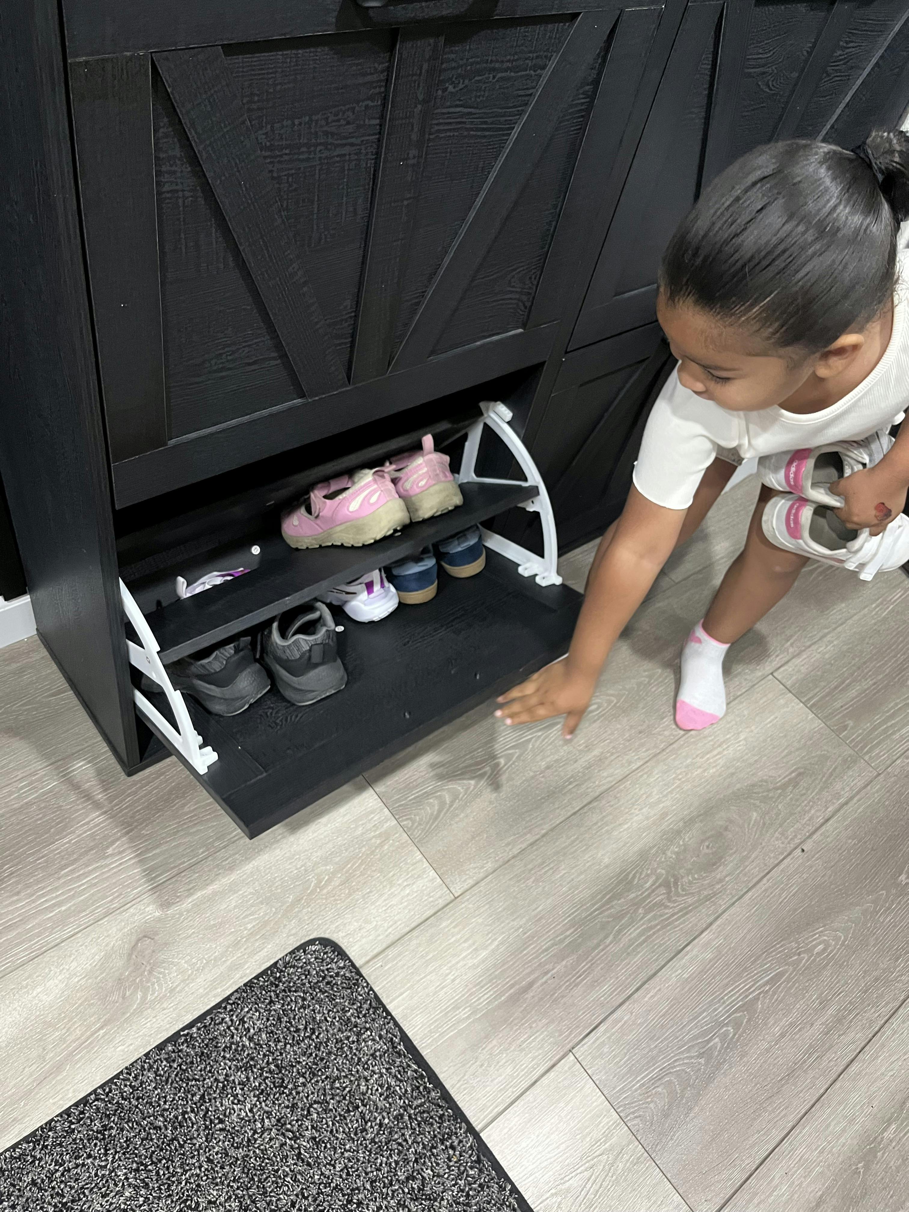 Child reaching into an open shoe cabinet to store footwear