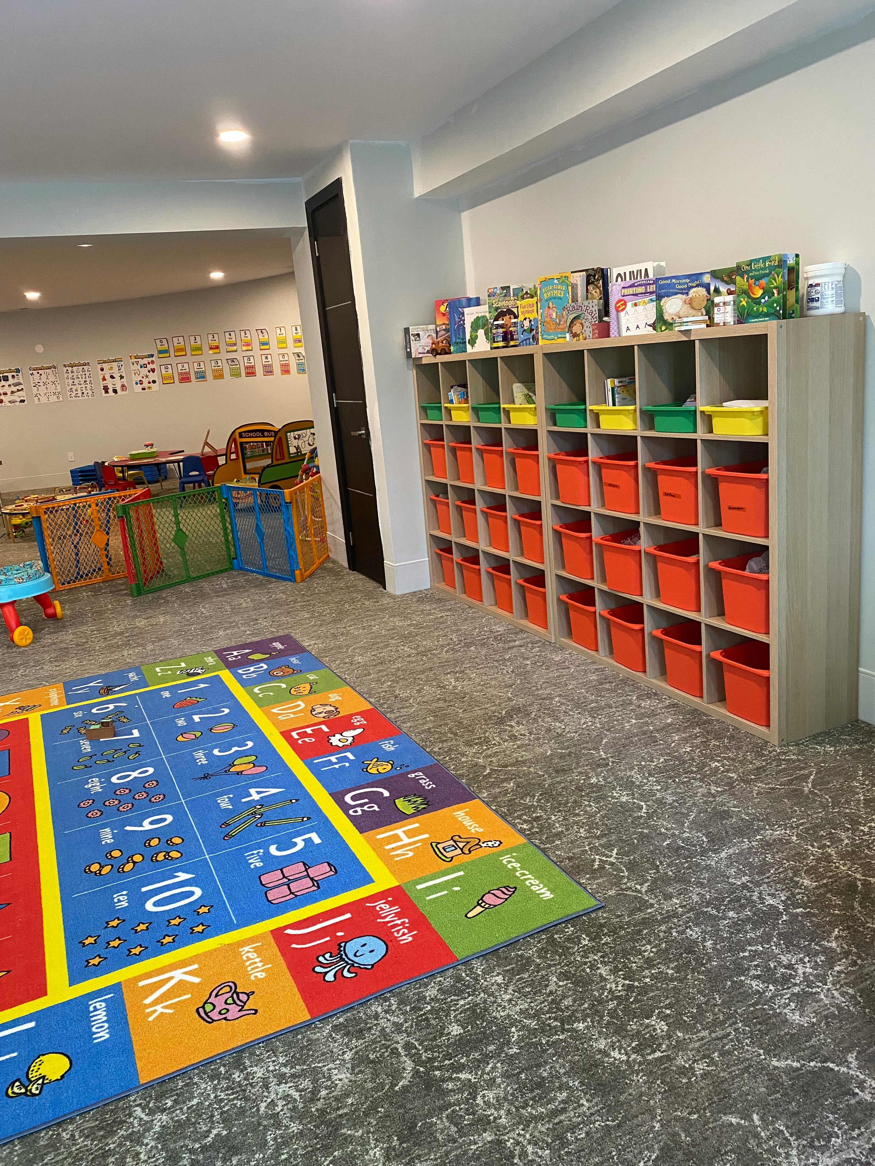 Playroom with an alphabet rug and storage shelves with orange bins
