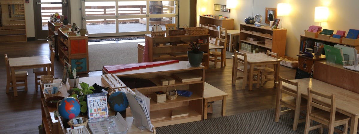 Classroom with small tables, chairs, and shelves with shelves of learning materials