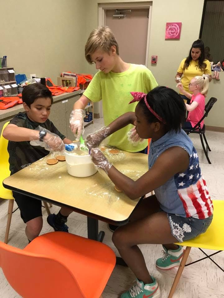 Three children and one teen mixing ingredients at a table