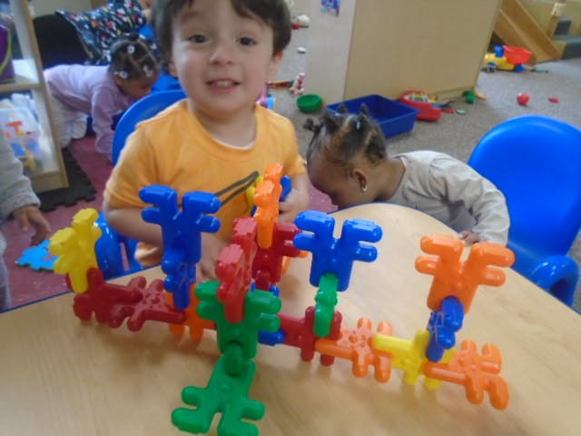 Child playing with colorful interlocking building toys on a table