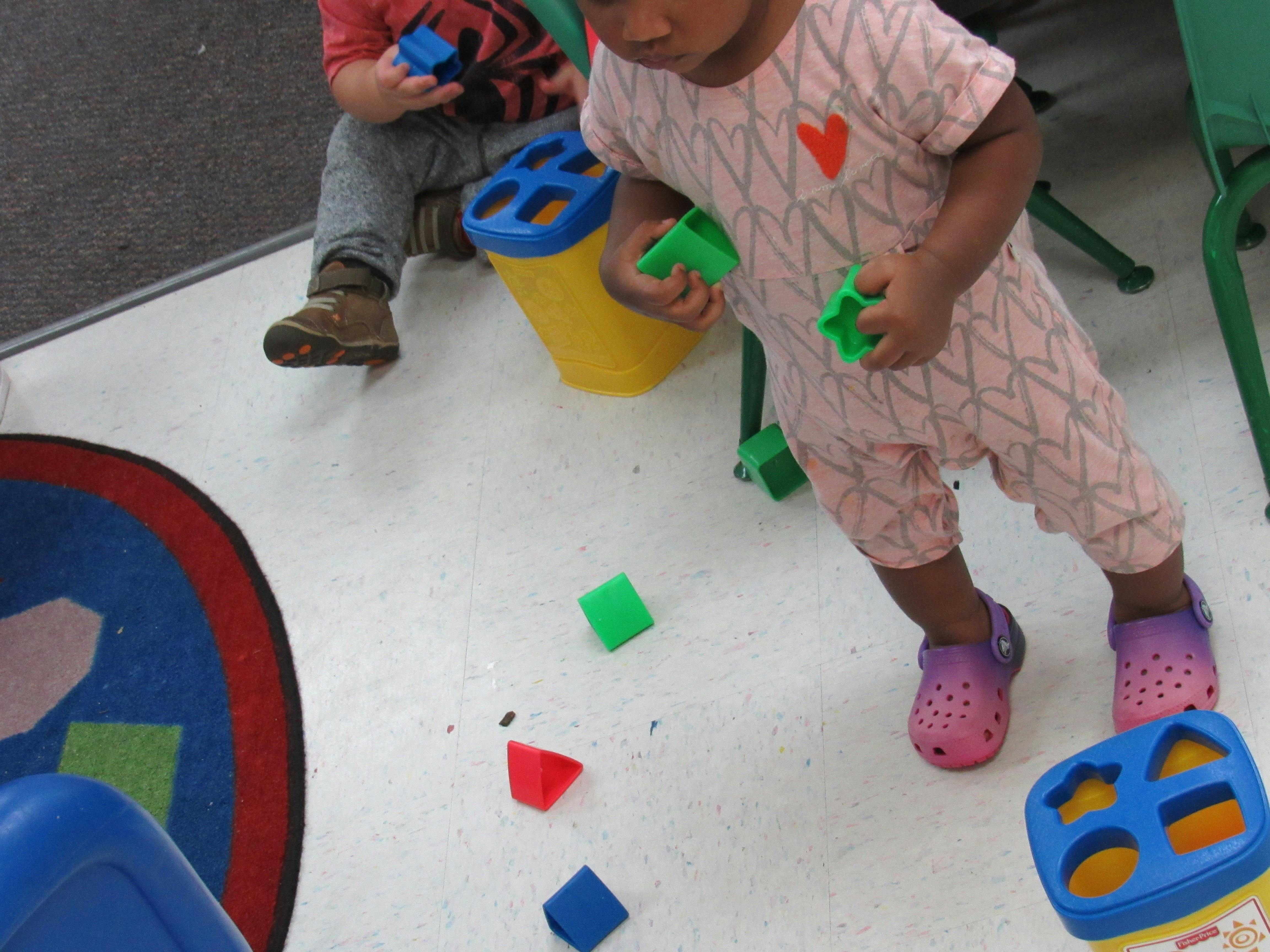 Children playing with colorful shape sorting toys on the floor
