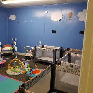 Nursery room with multiple cribs and infant play equipment