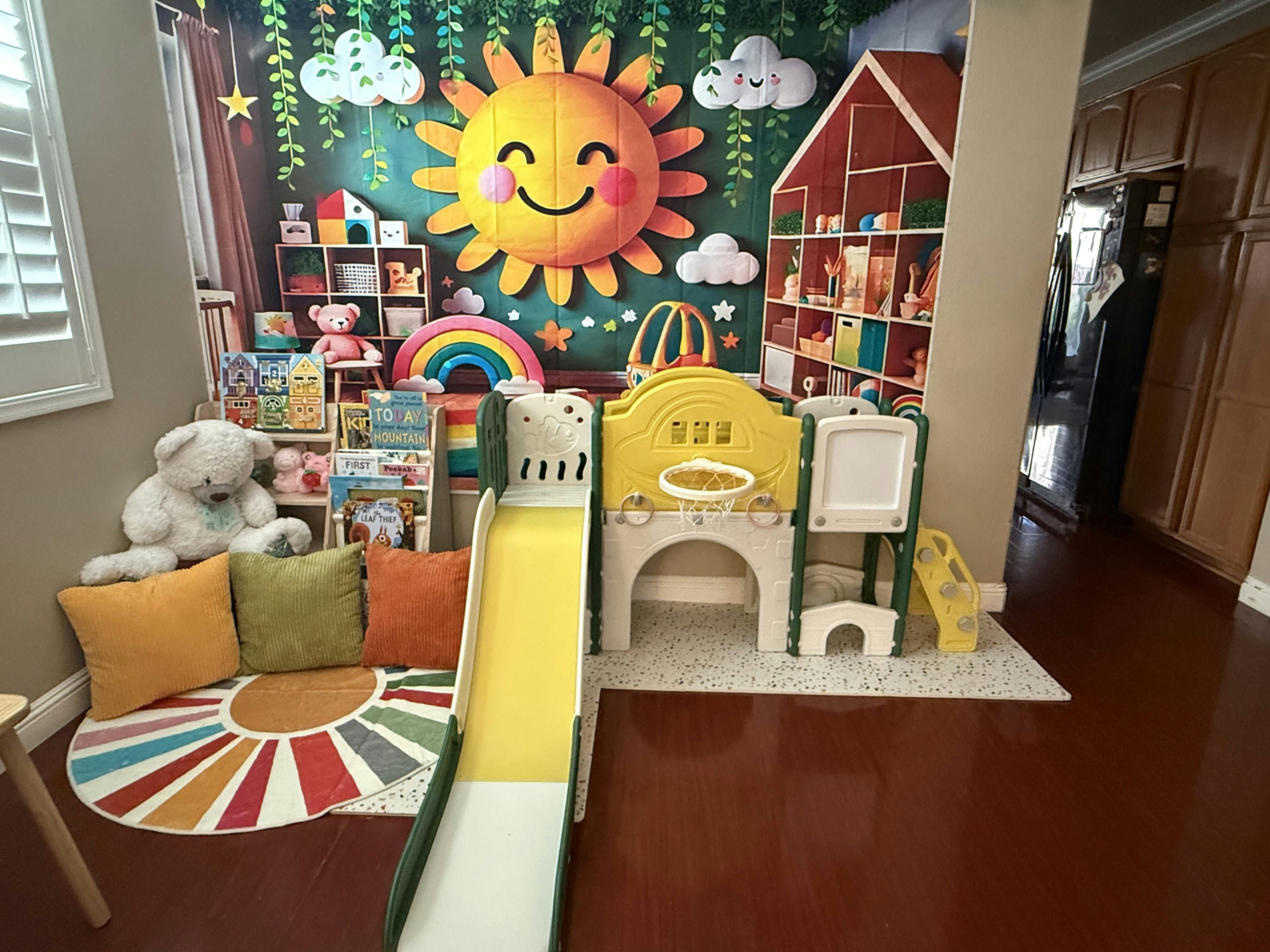 Indoor play area with slide, basketball hoop, stuffed animals, and large sun mural