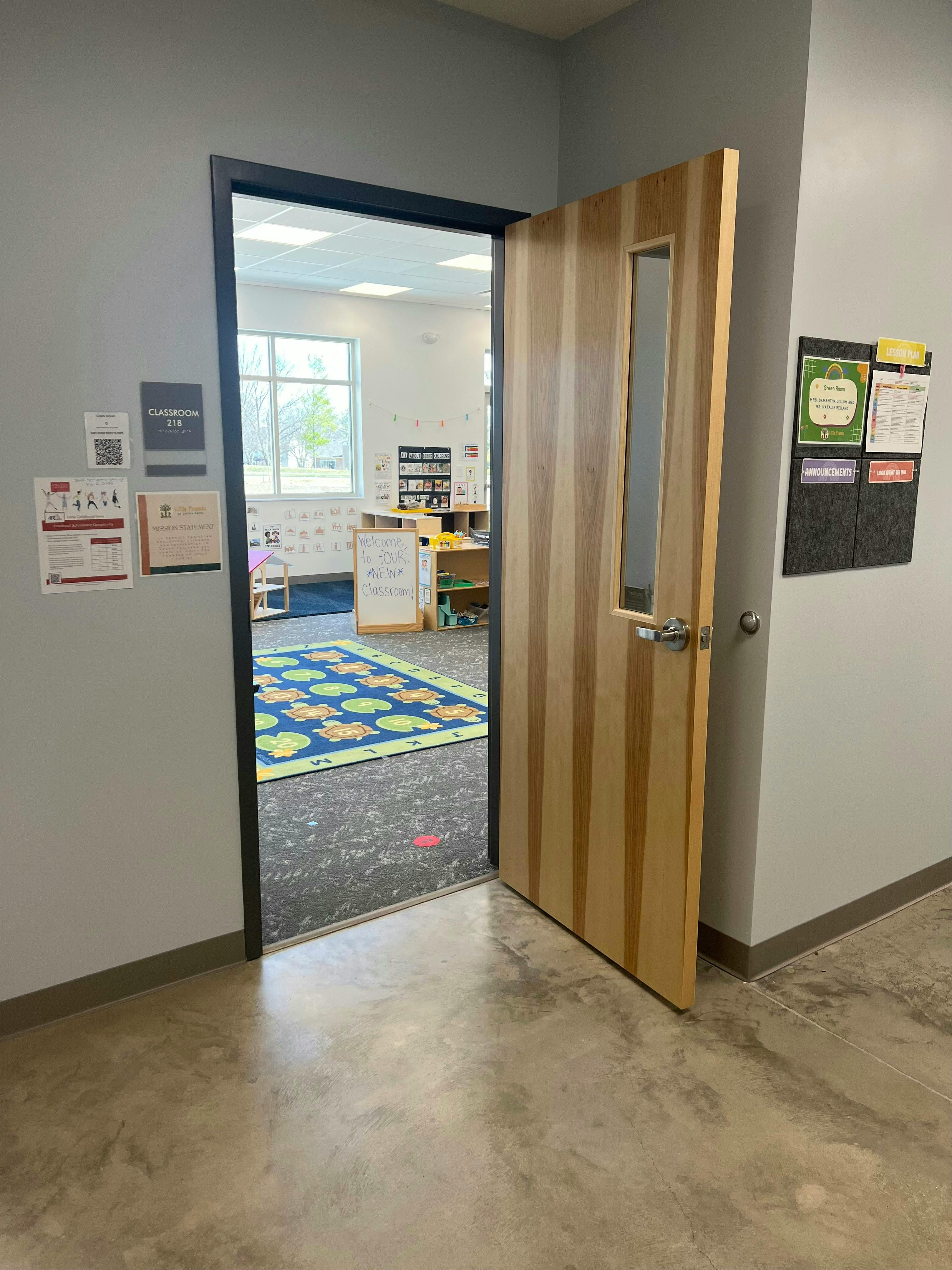 Open door to a classroom with a colorful rug