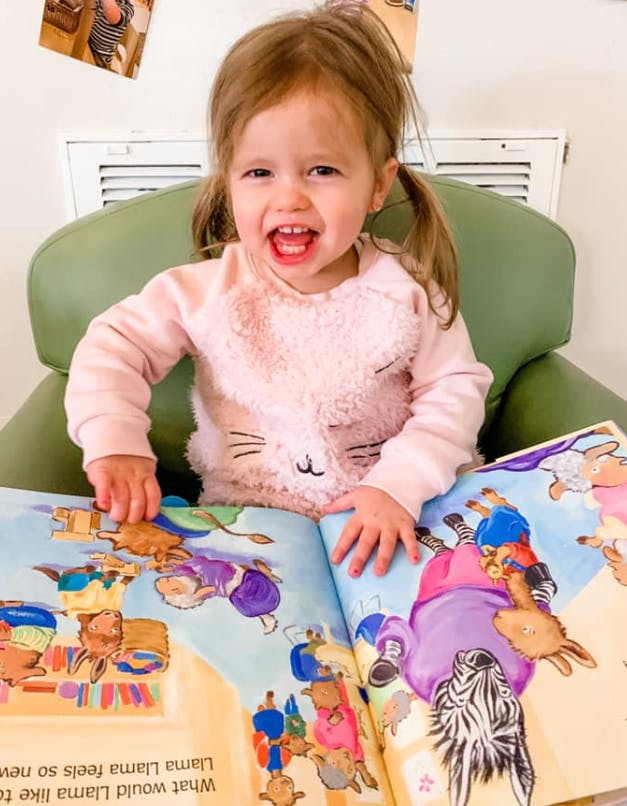 Child sitting in a chair with an open book in front of them