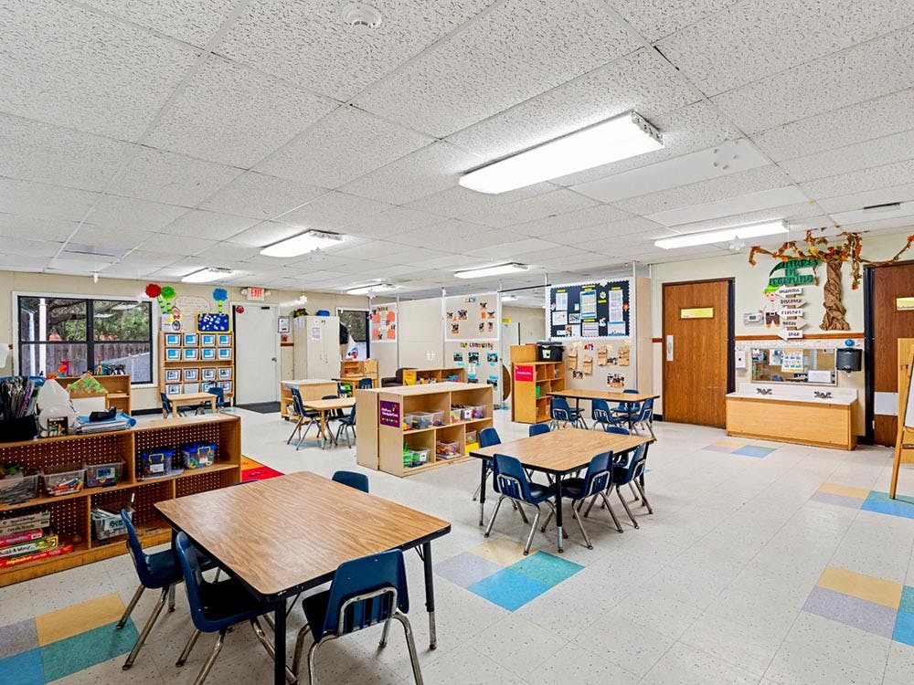 Empty preschool classroom with small tables and chairs