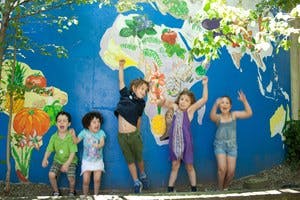Five children standing in front of a world map mural