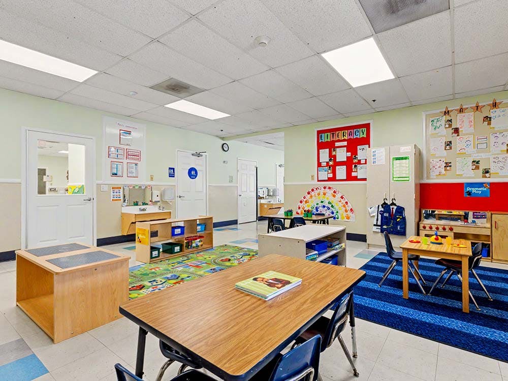 Empty colorful preschool classroom with small tables and chairs