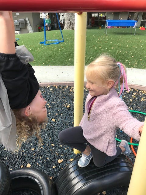Child hanging upside down and another child kneeling on a tire