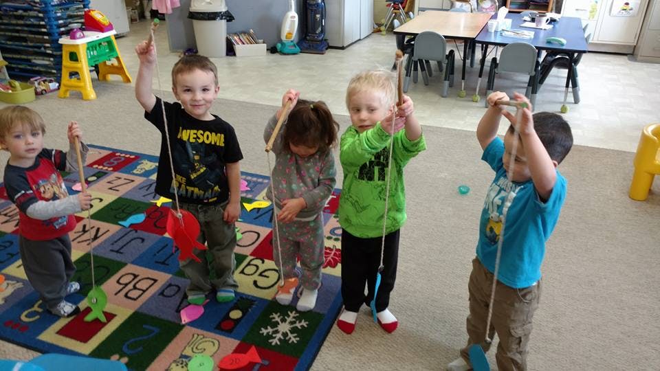 Children playing with fishing toys in a classroom