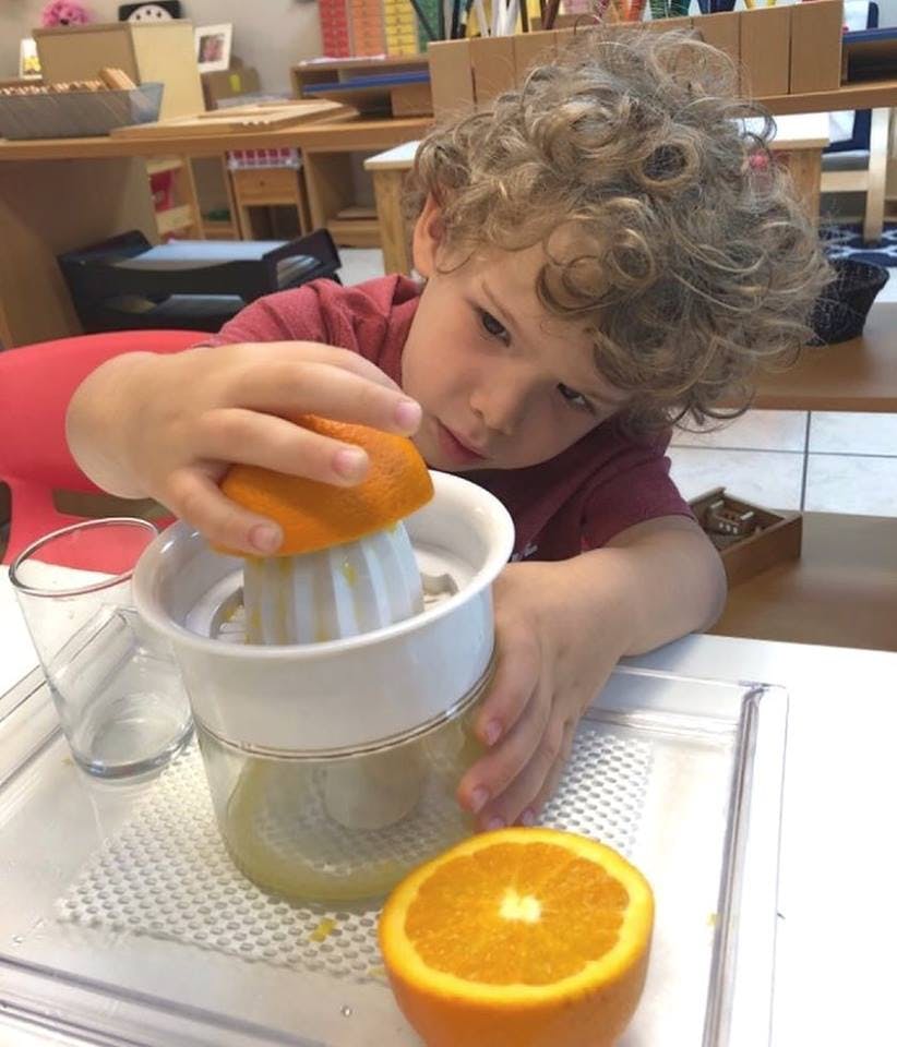 Child squeezing an orange half with a juicer