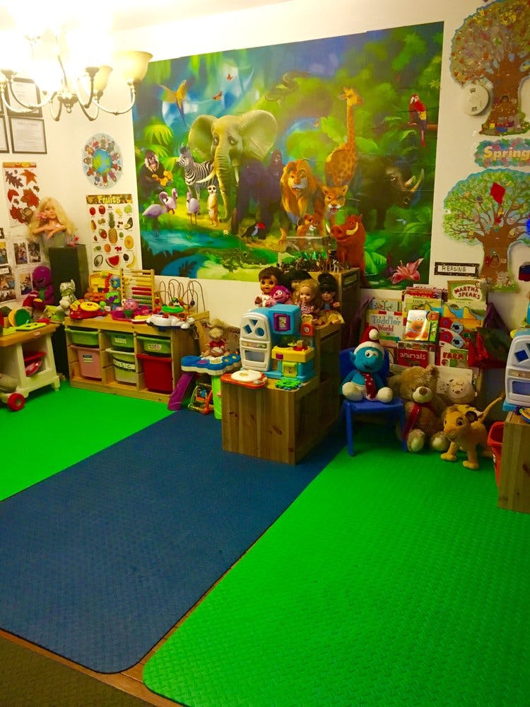Playroom with green and blue floor mats, toys, and a jungle mural