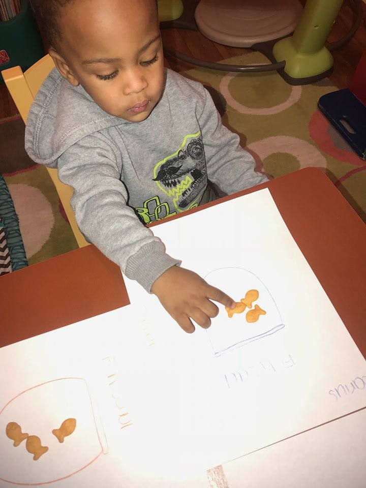 Child pointing at goldfish crackers on a paper