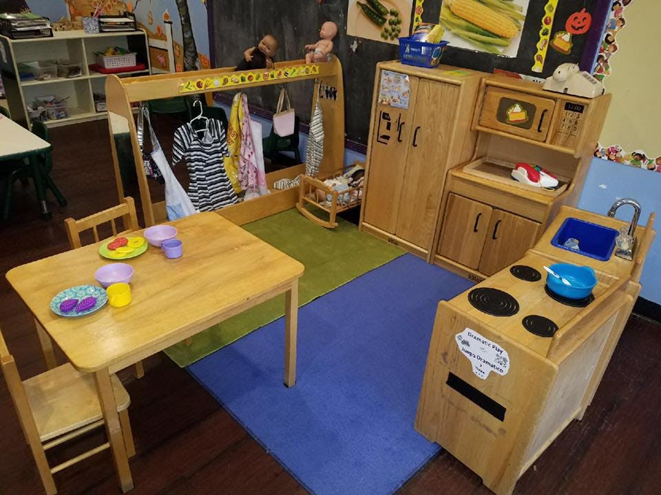 Playroom with wooden play kitchen, table and chairs, and dress-up rack