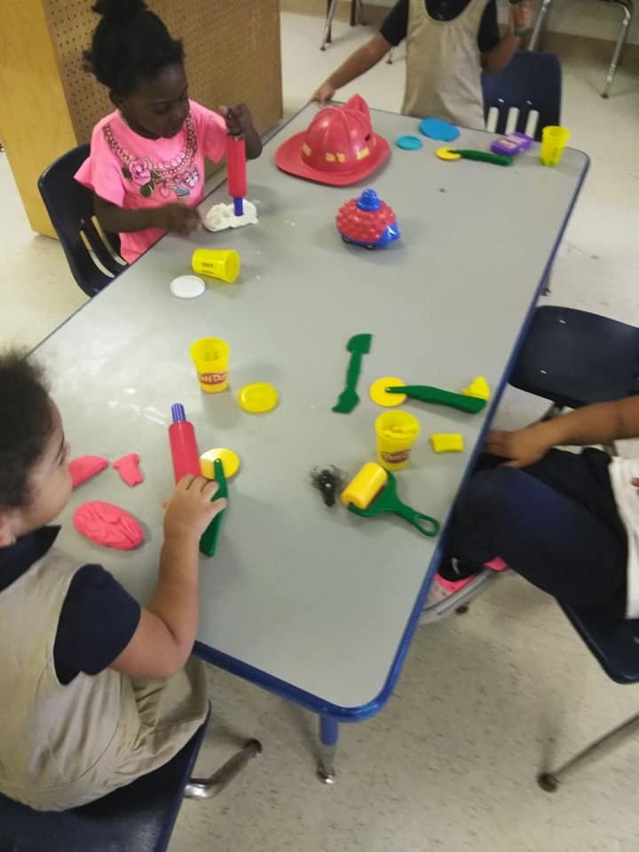 Children playing with modeling clay and tools at a table