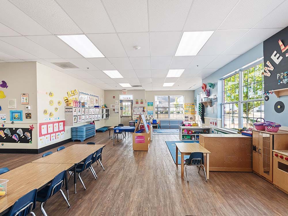 Empty preschool classroom with small tables and chairs