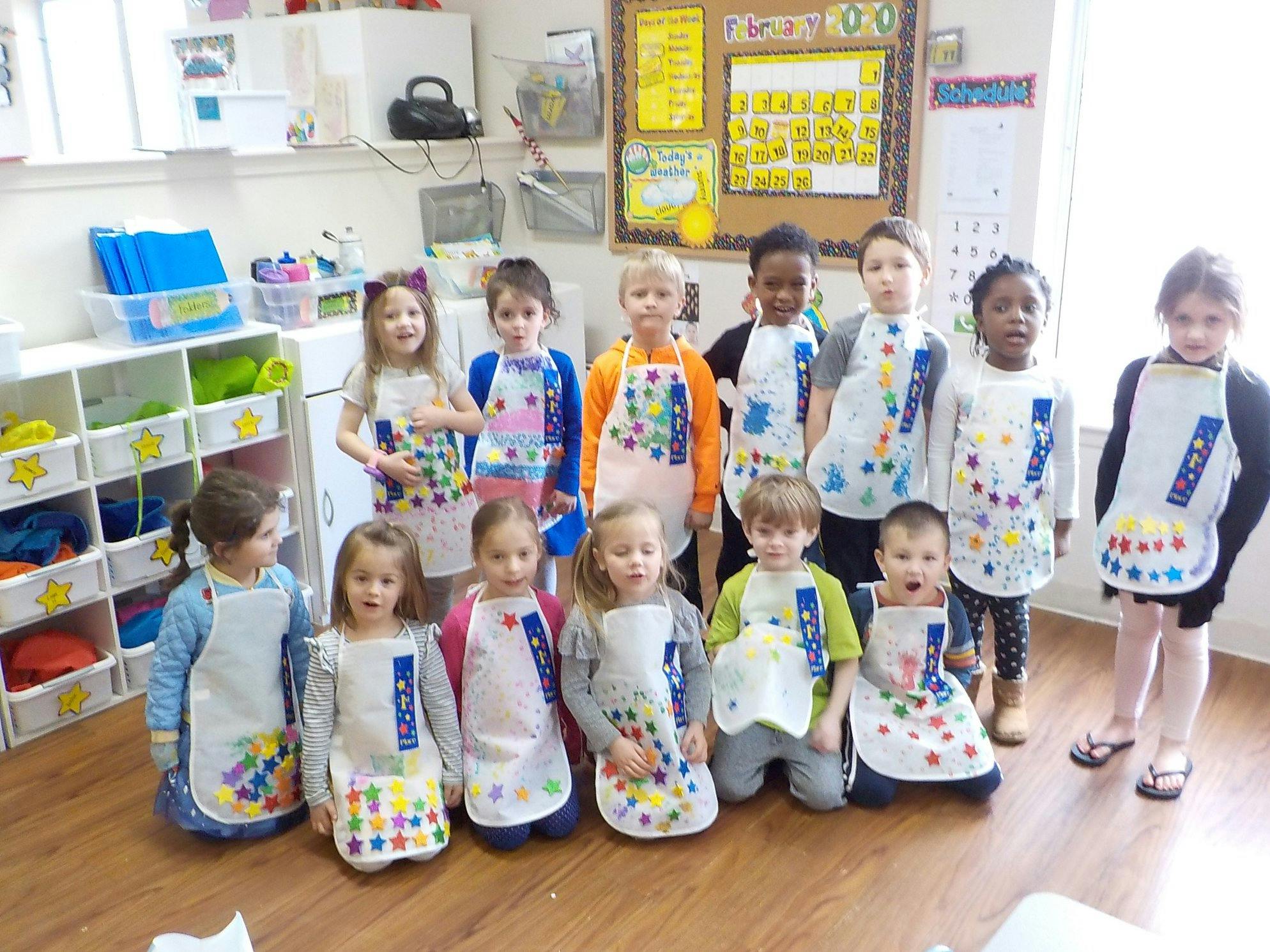Group of children wearing aprons in a classroom