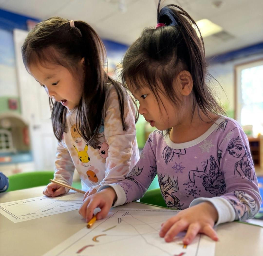 Two children working on worksheets at a table