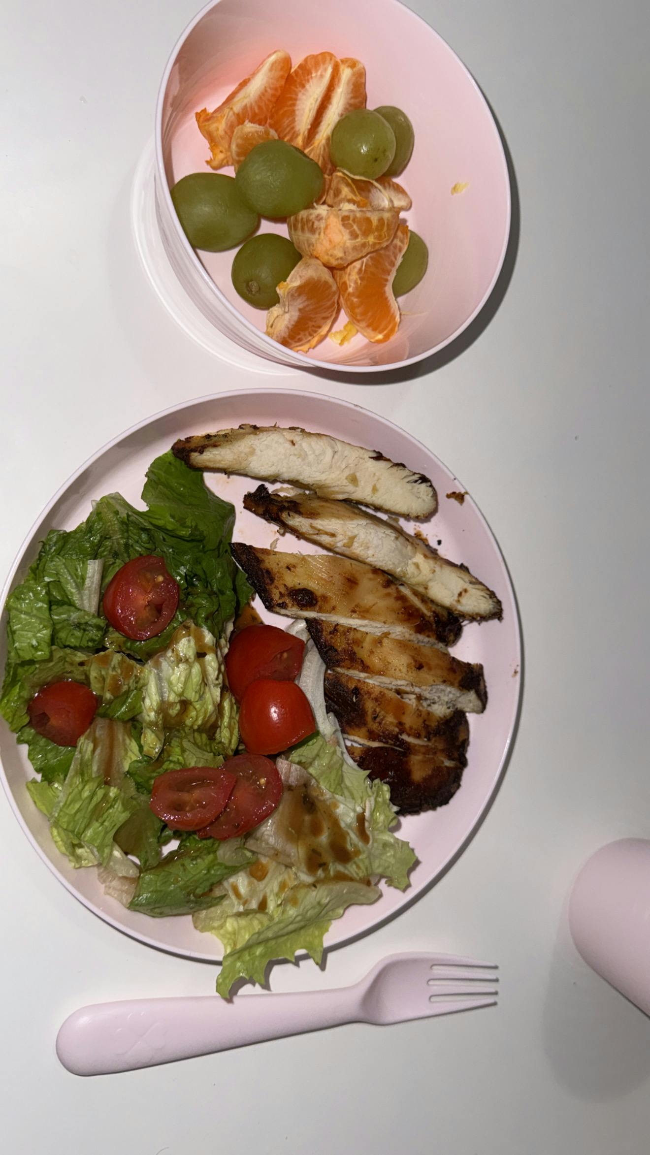 Plate of grilled chicken and salad with a bowl of fruit