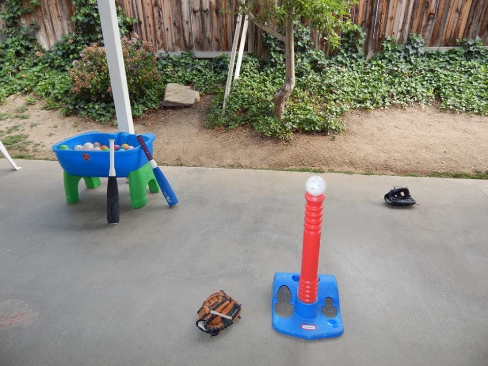 T-ball stand with a ball, baseball glove, and a blue table with bats and balls