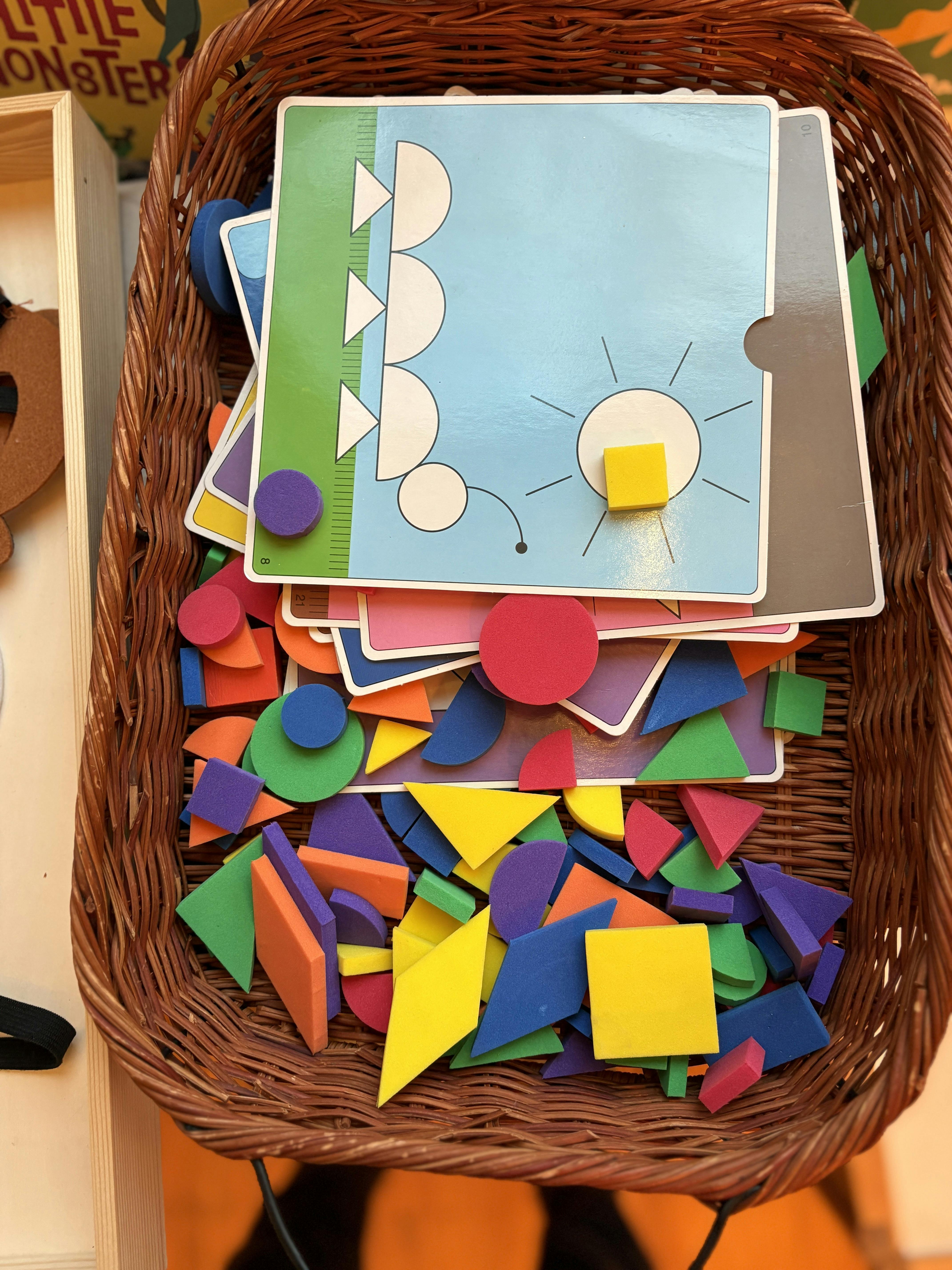 Wicker basket filled with colorful foam geometric shapes and pattern cards