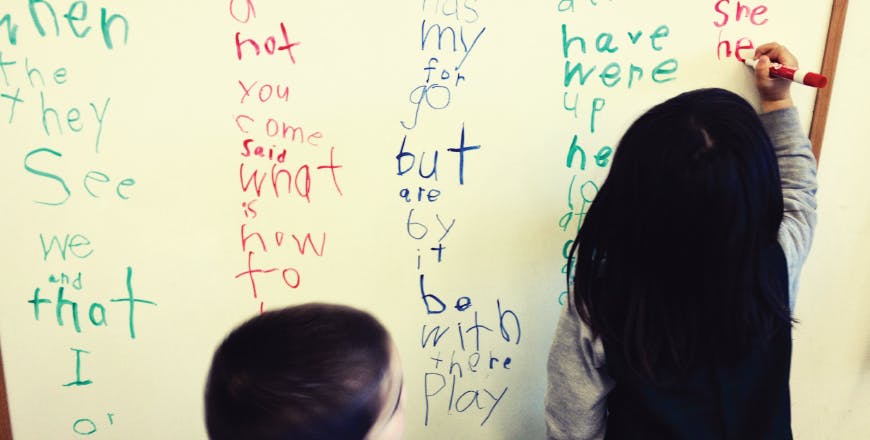 Child writing on a whiteboard with colorful markers