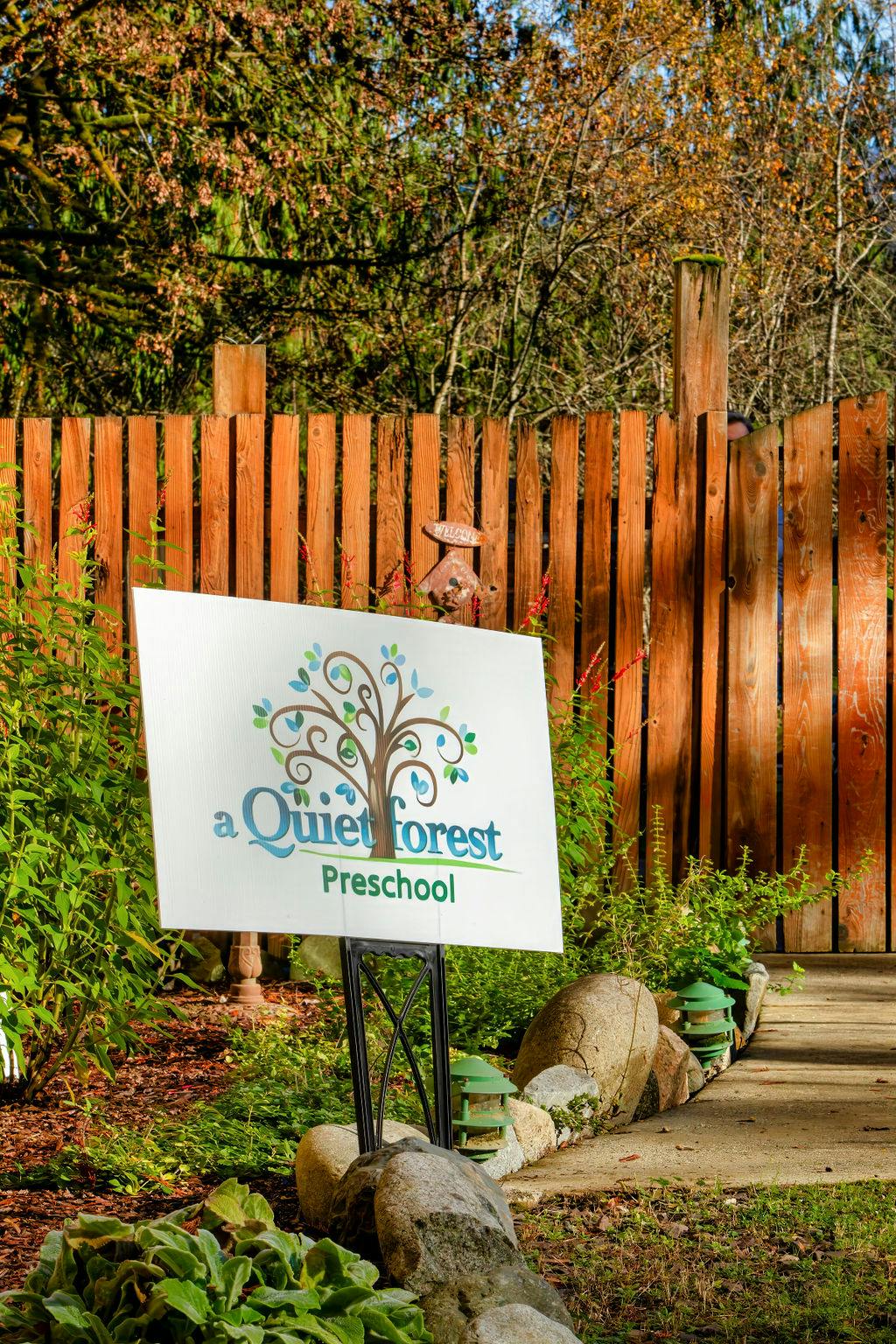 A Quiet Forest Preschool sign with a tree logo in a garden setting