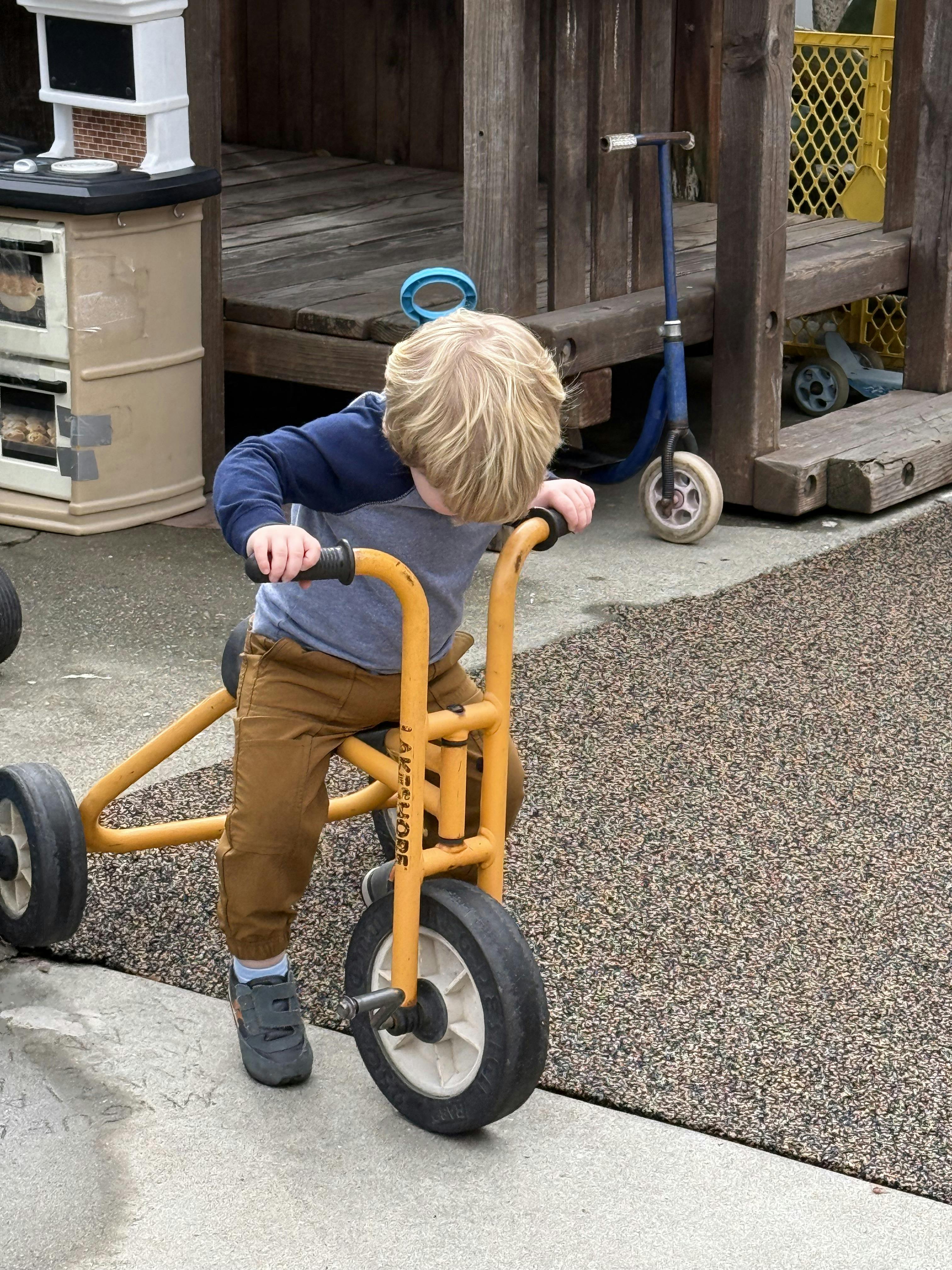 Child riding a yellow tricycle outdoors