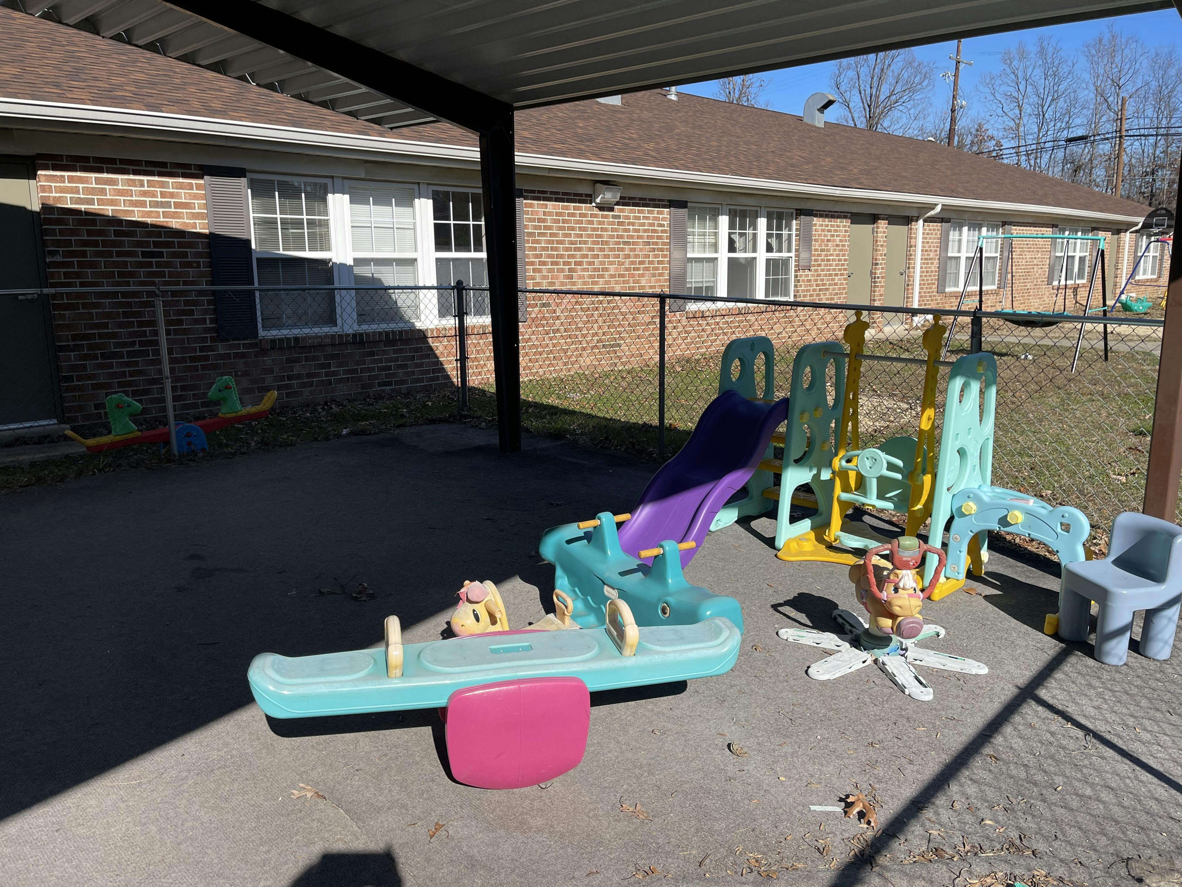 Playground area with plastic slide, seesaw, and other play equipment