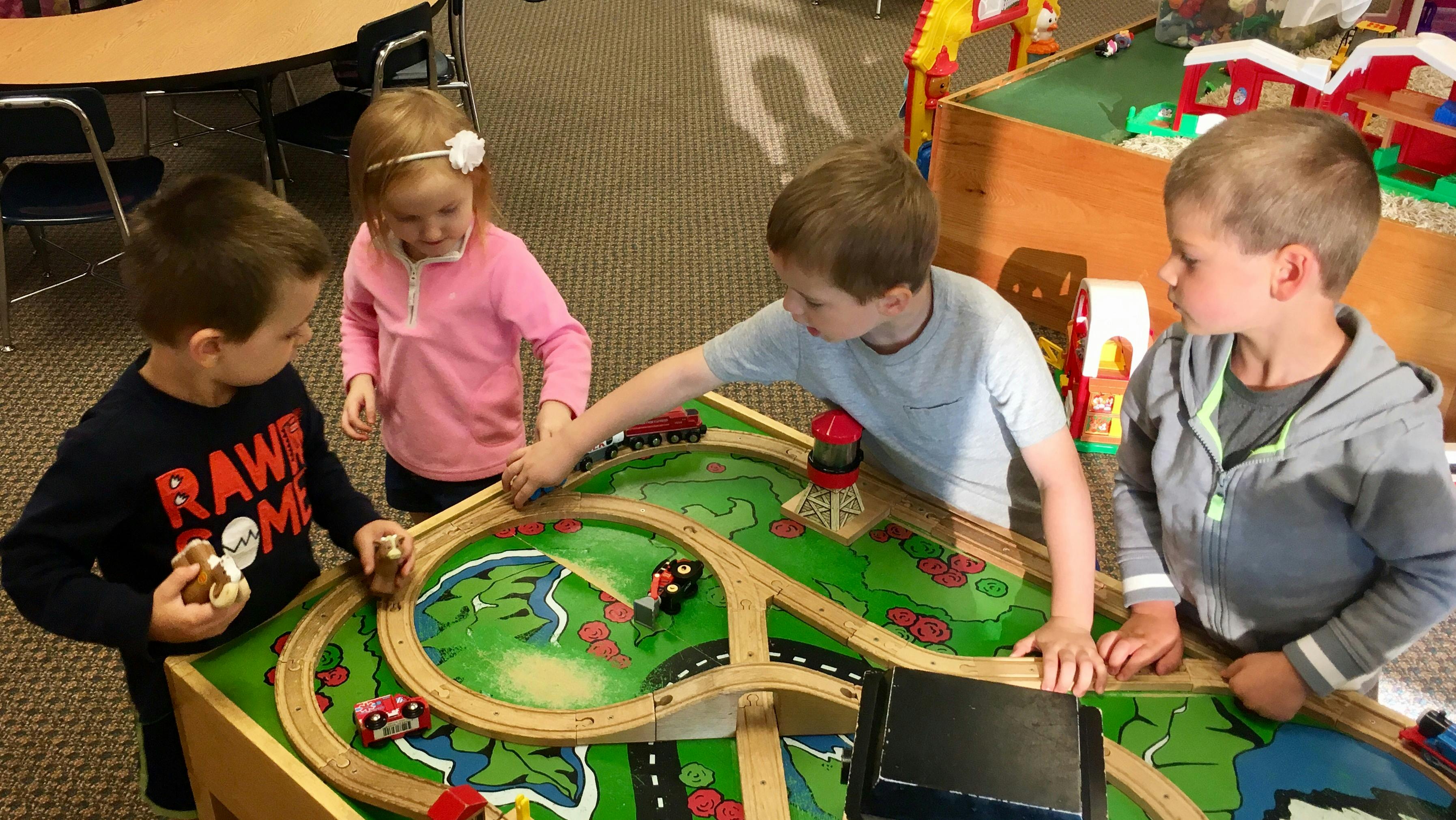 Four children playing with a toy train set
