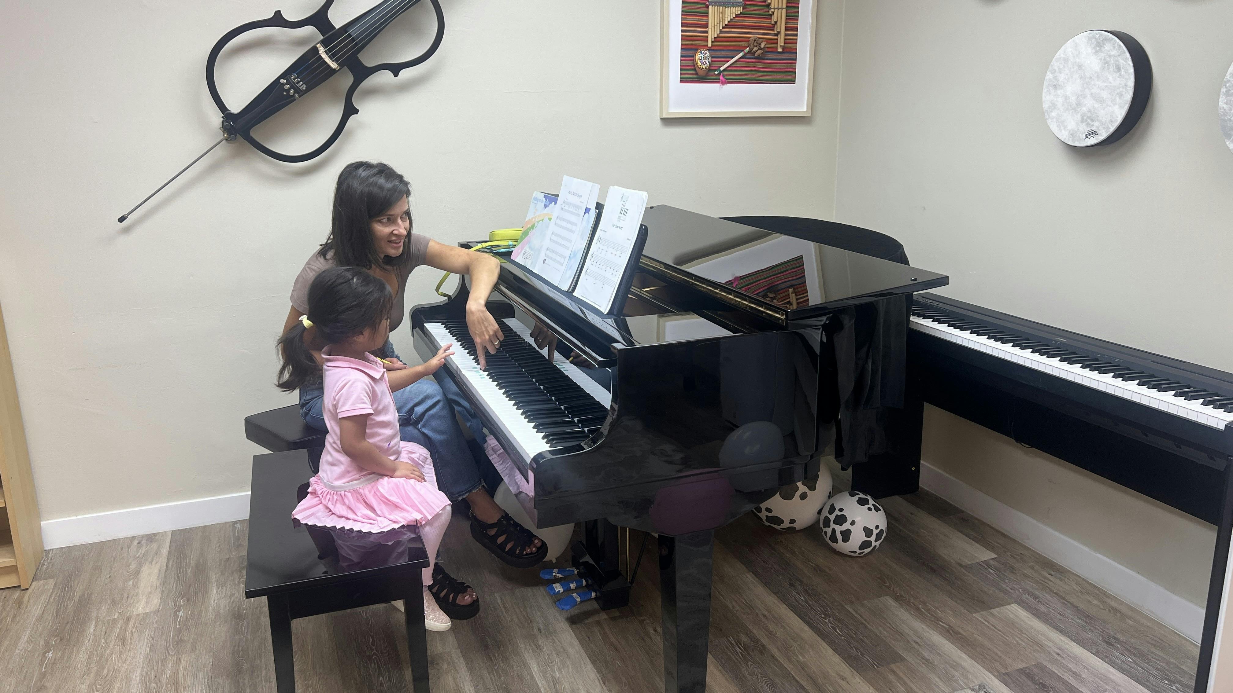 Adult and child playing a piano during a lesson