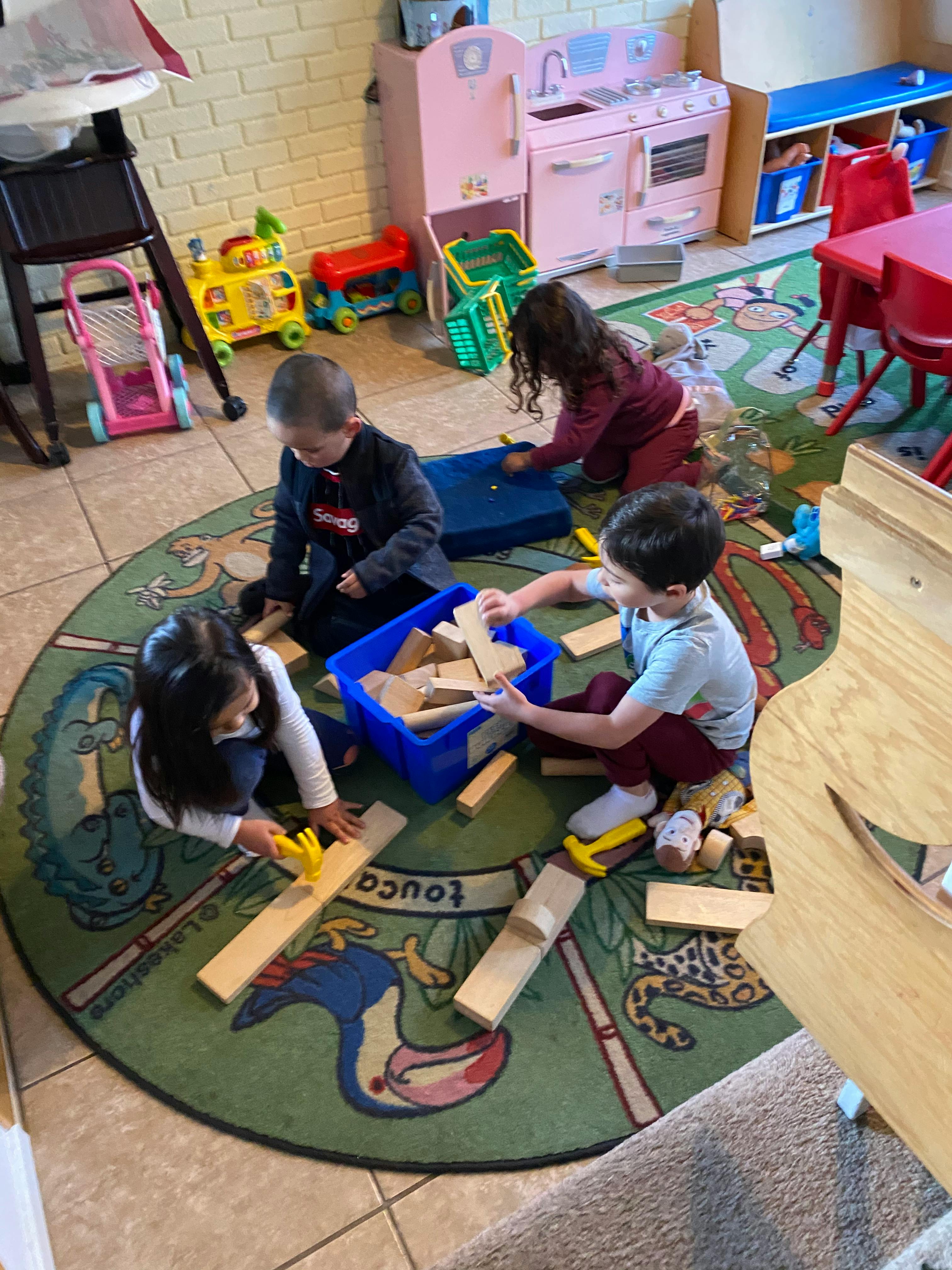 Children playing with wooden blocks on a rug in a classroom