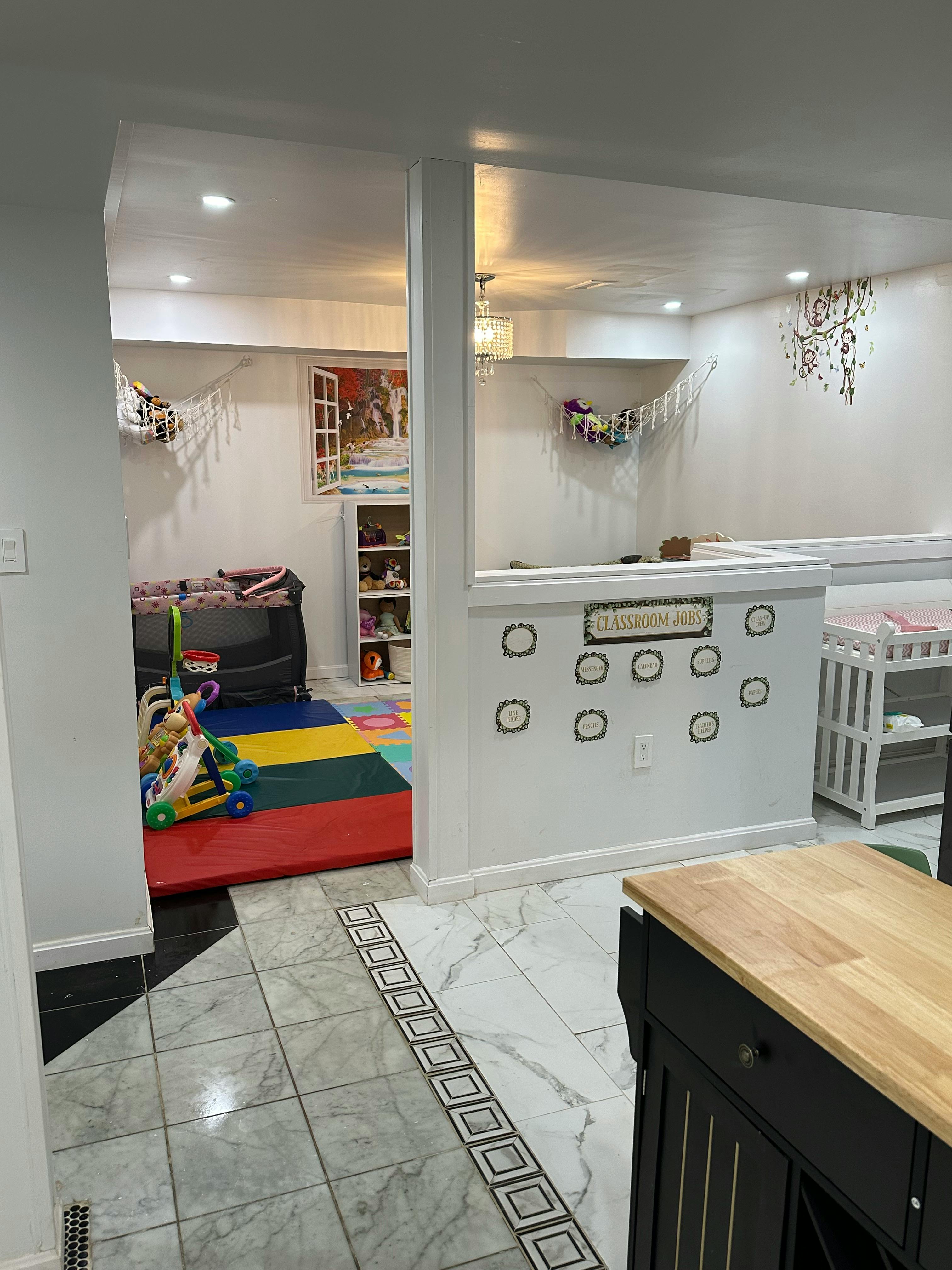 Playroom with colorful mat, toys, and cribs