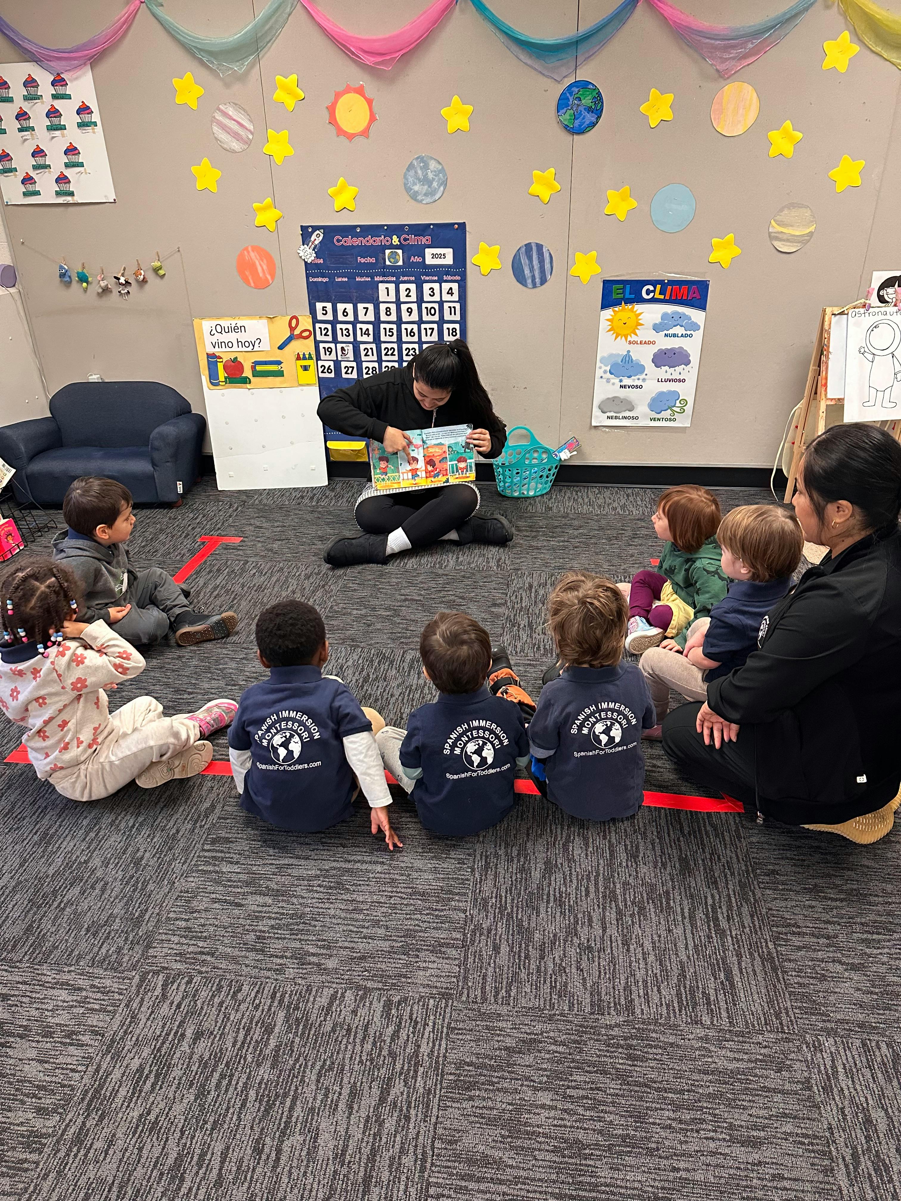 Adult reading a book to a group of children in a classroom
