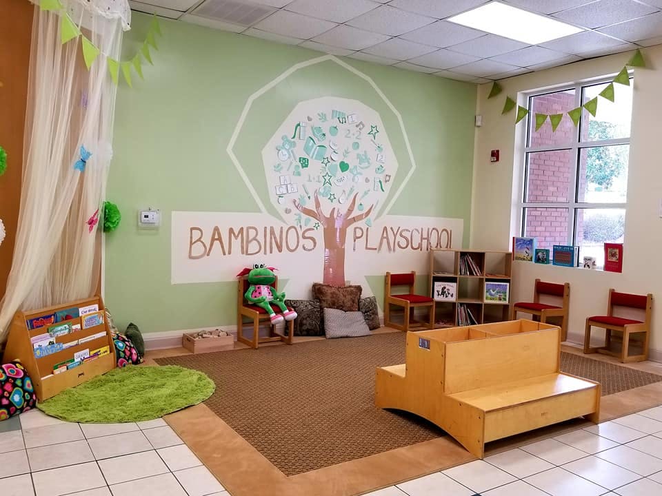 Playroom with a tree mural and "Bambino's Playschool" text on the wall