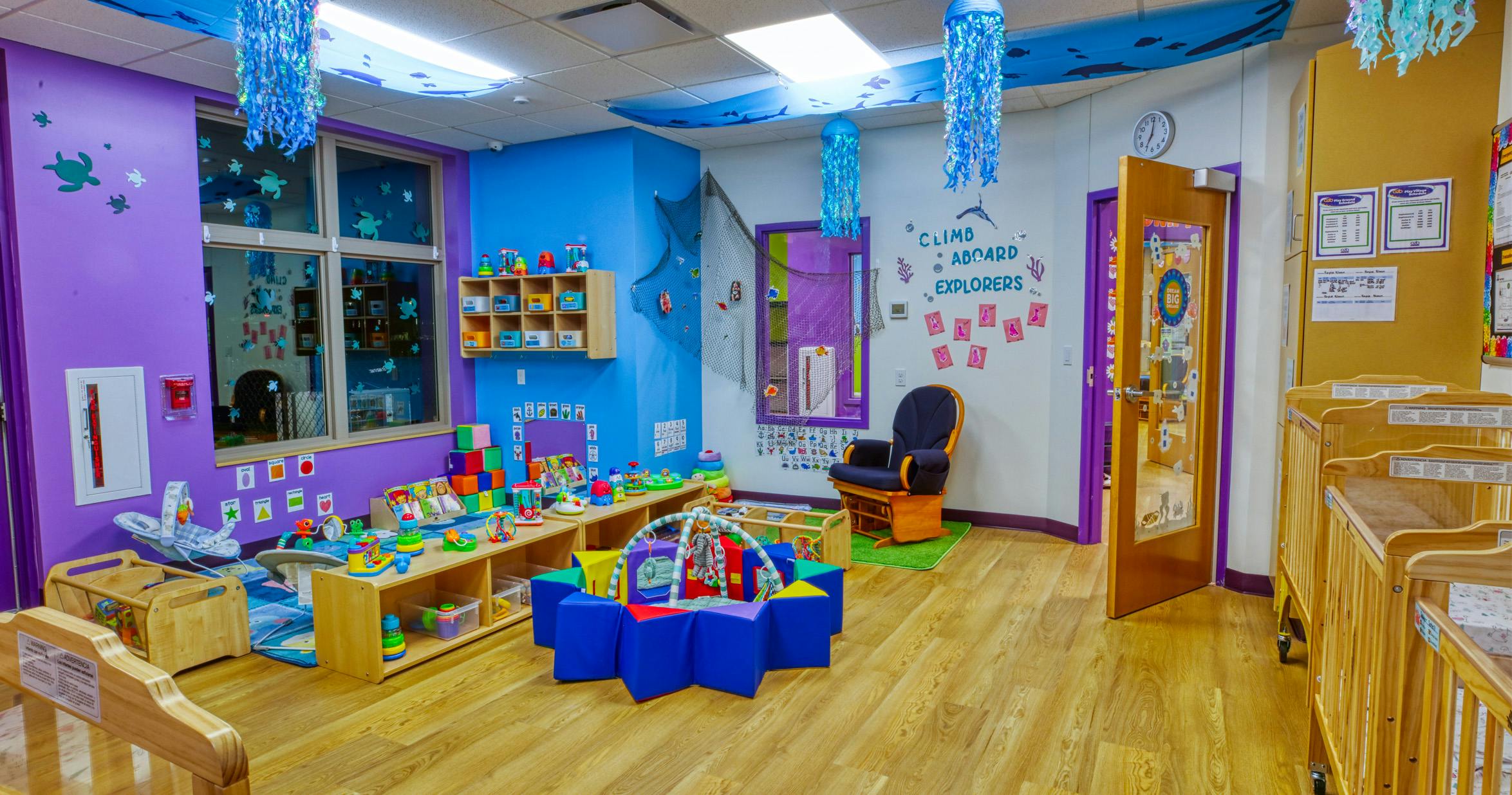 Colorful playroom with toys, activity centers, and cribs