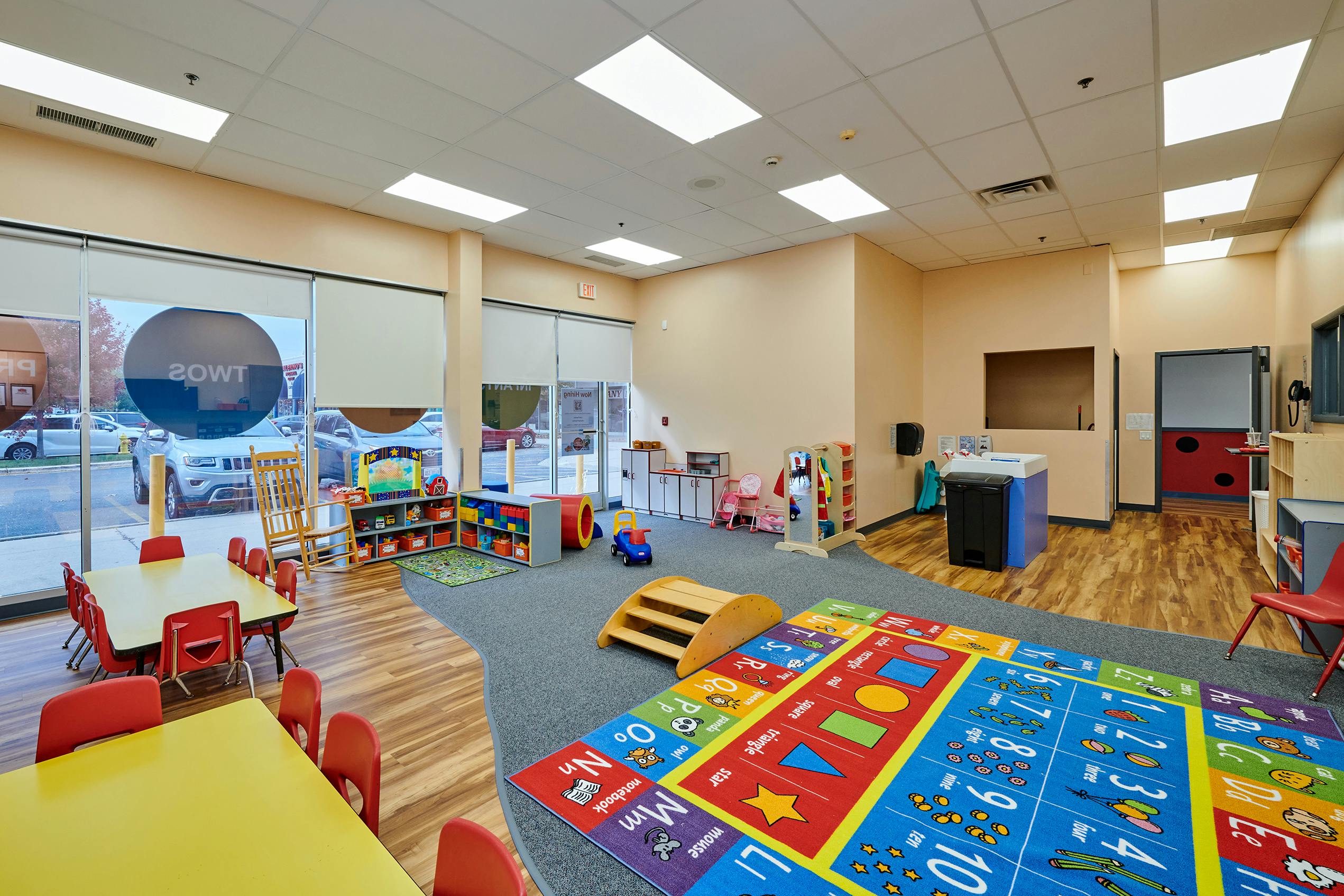 Empty classroom with colorful play mats and small tables
