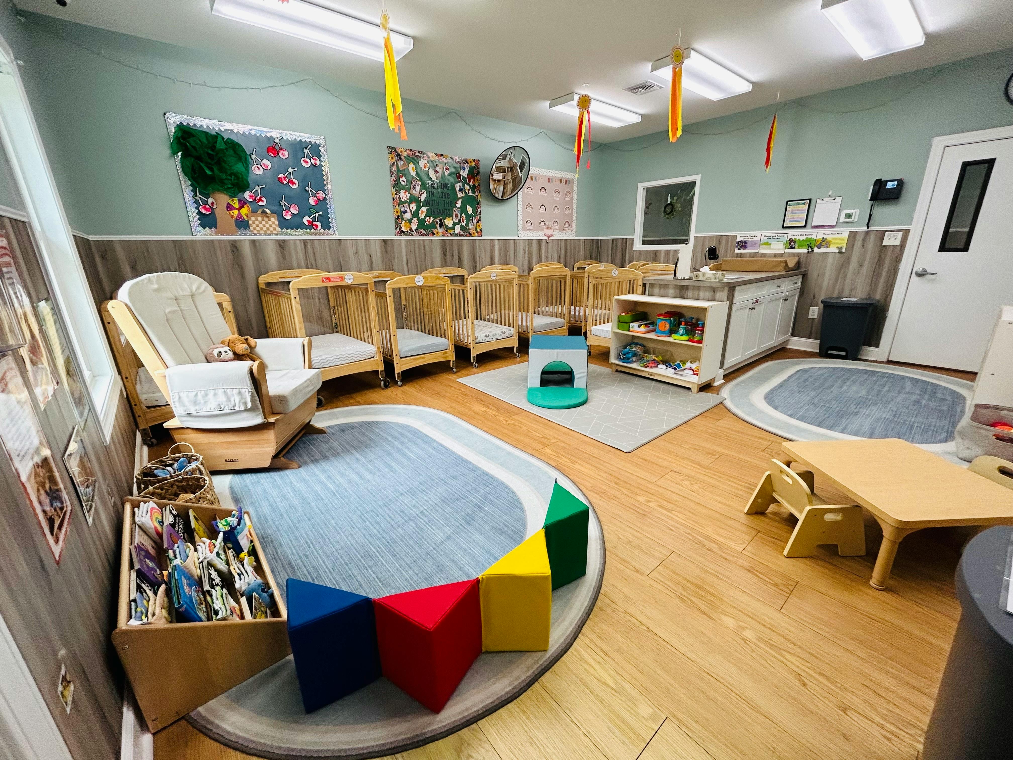 Daycare room with cribs, a rocking chair, and play mats