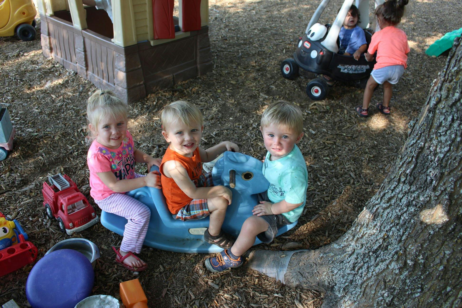 Three children on a blue rocking toy