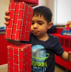 Child stacking red brick-patterned blocks