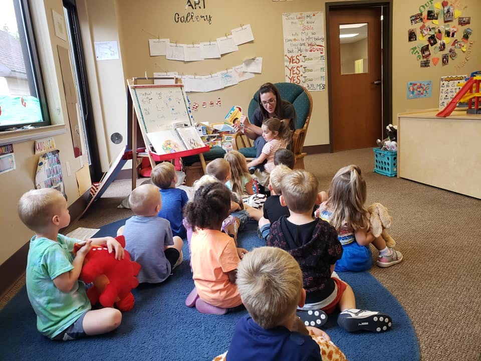 Person reading to a group of children in a classroom