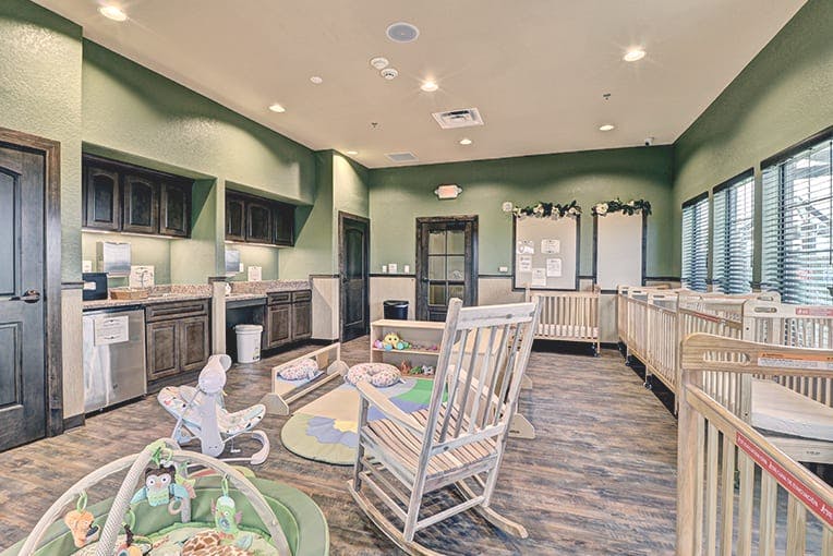 Nursery room with cribs, rocking chair, and changing station