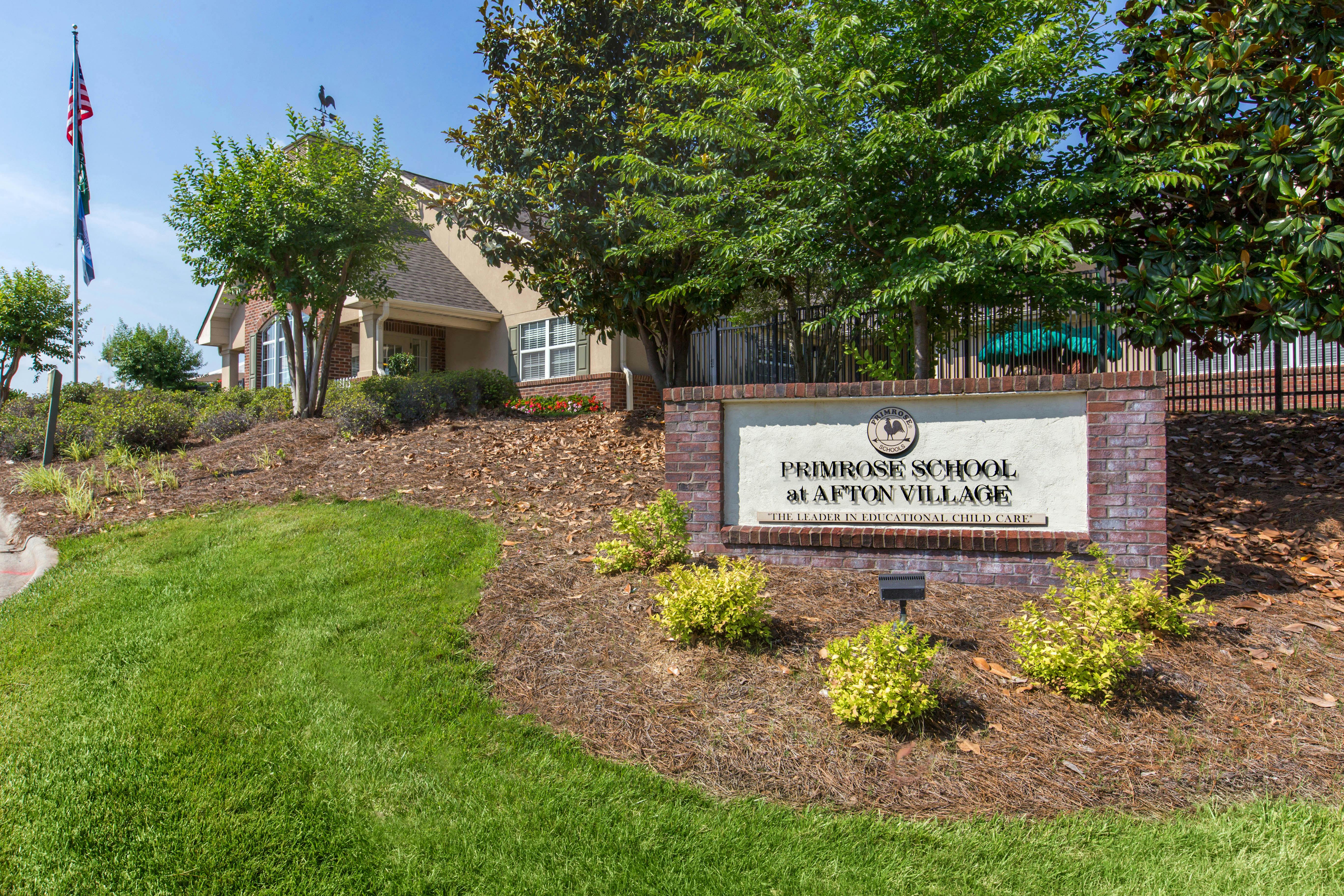 Primrose School at Afton Village sign with a building and flagpole in the background