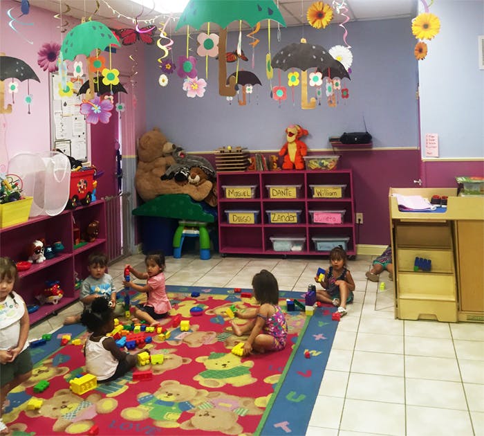 Children playing with blocks on a colorful rug in a classroom