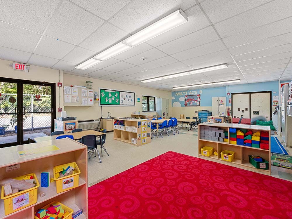 Empty classroom with tables, chairs, and shelves of learning materials