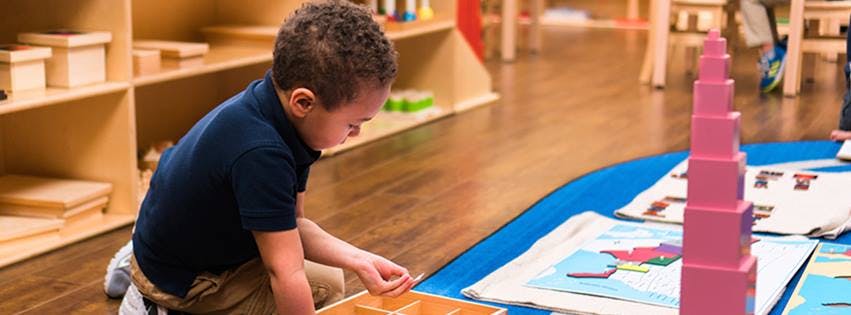 Child playing with wooden blocks in a classroom