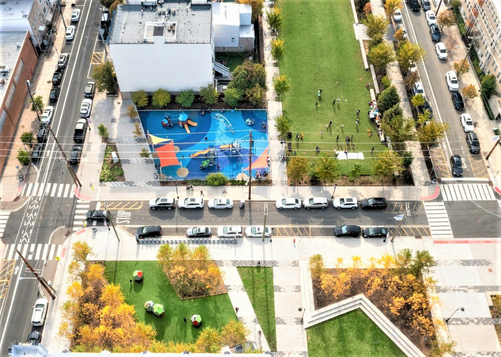 Aerial view of a city park with a playground, green spaces, and streets
